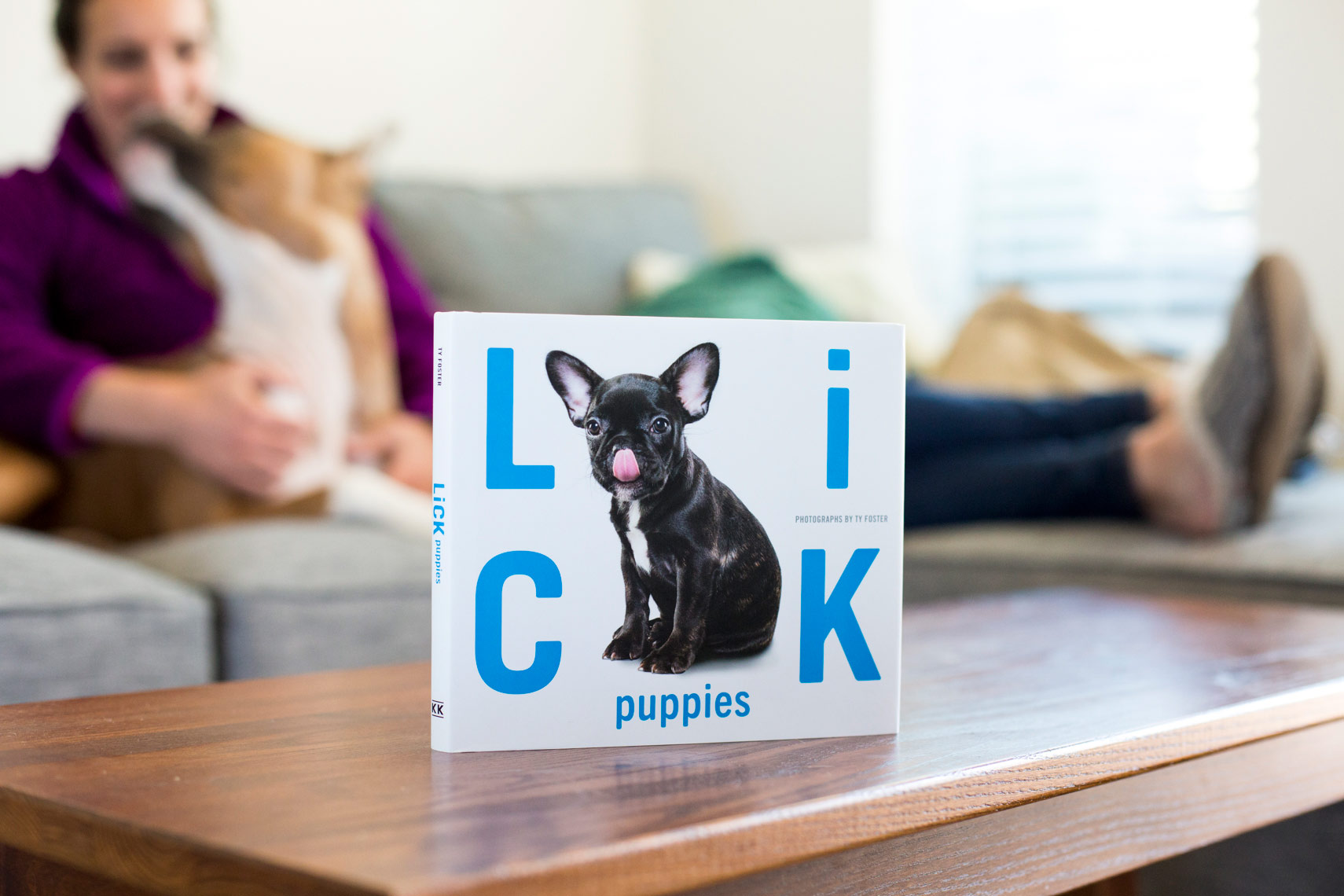 A happy girl and her dog with a LICK puppies book on their coffee table